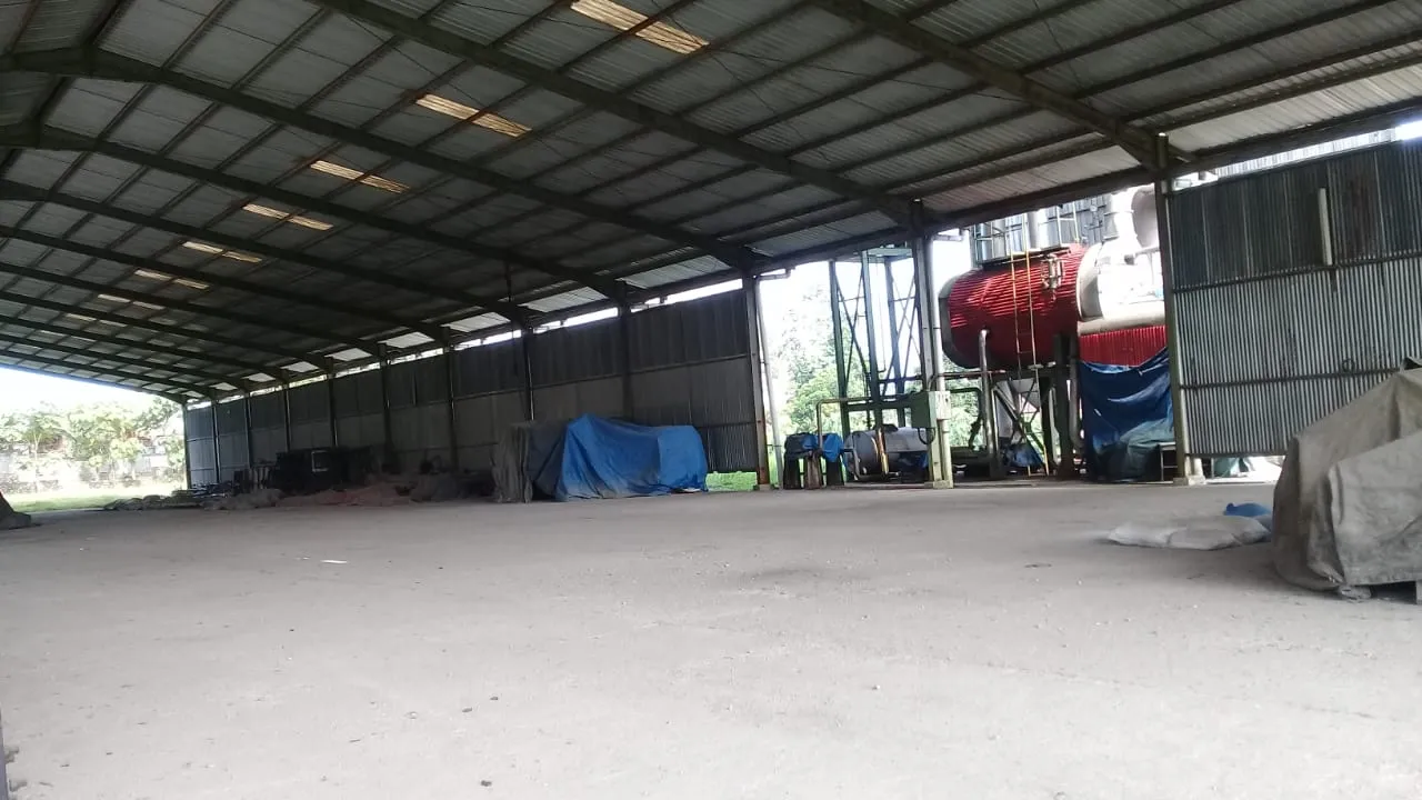 厂区带顶生产车间，内有锅炉与堆放物料，混凝土地面
